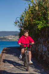 Niño con una bicicleta en paseo marítimo con el mar de fondo