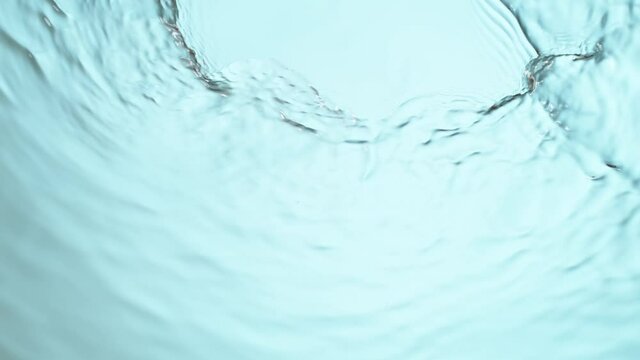 Super slow motion of water surface on light blue background. Filmed on high speed cinema camera, 1000 fps.