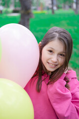 Naklejka premium pretty tween teenager brunette girl in pink holding colorful hot air balloons outdoors. party, birthday concept. summertime. happy children. hollidays, summer break