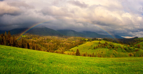Rainbow in the mountains, amazing nature summer landscape with green alpine meadow, mountain range...