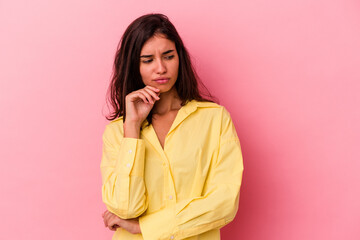 Young caucasian woman isolated on pink background looking sideways with doubtful and skeptical expression.