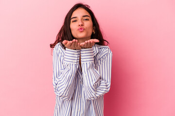 Young caucasian woman isolated on pink background folding lips and holding palms to send air kiss.