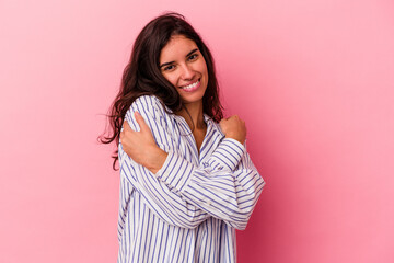 Fototapeta premium Young caucasian woman isolated on pink background hugs, smiling carefree and happy.