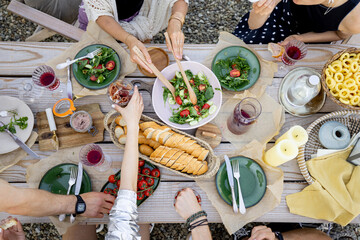 Group of people dining outdoors, view from above on the beautifully decorated wooden table with healthy food and drinks