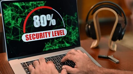 Hand using laptop computer with security level motion graphic displayed on screen from zero to 100 percent