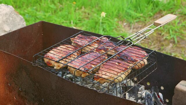 The grill with fried meat lies on the mongala, the coals are smoking. The stage of self-cooking barbecue. Making food over an open fire. Outdoor picnic in nature. Warm day, soft sunshine. Close-up.
