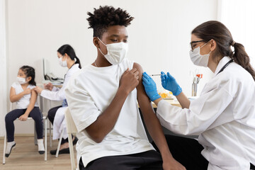 Obraz premium young male african wearing medical face mask and getting vaccinated from doctor, to build up or maintain immunity