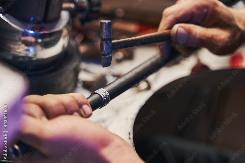 Wall mural Goldsmith shop worker hitting ring with ball-peen hammer