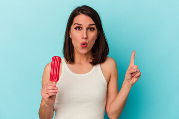 Young caucasian woman holding an ice cream isolated on blue background having some great idea, concept of creativity.