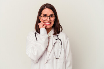 Young doctor caucasian woman isolated on white background biting fingernails, nervous and very...