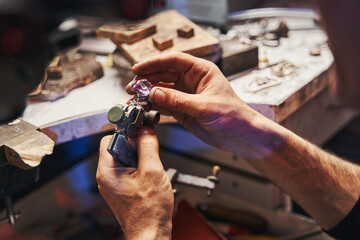Male jeweler turning amethyst on gem-cutting tool