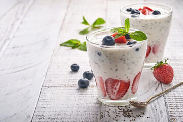 Two strawberry chia seeds layered smoothie or milkshake with strawberry and blueberry mint in glass on light grey background. Summer and healthy dieting drinks, vegetarian food concept.