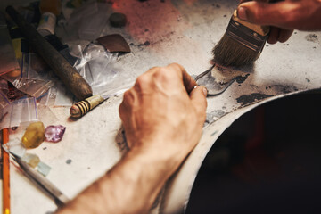 Jeweler sweeping away dust from table to little shovel