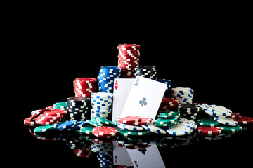 Obraz premium Stack of Casino gambling chips and cards isolated on black reflective background