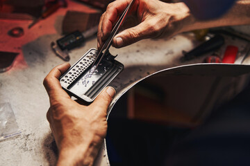 Jeweler picking up diamonds from steel tray with tweezers