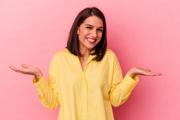 Young caucasian woman isolated on pink background makes scale with arms, feels happy and confident.