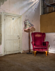 Empty chair in abandoned old house with lamp and door, chink of light.