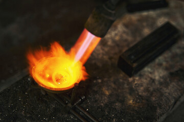 Flame from blowtorch melting metal for jewelry piece