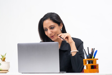 Portrait of professional Indian businesswoman working from her computer, Freelancer, work from home, Corporate lady holding pencil and concentrating.