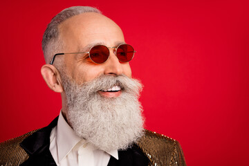 Photo of charming cheerful young man look empty space wear sunglass smile isolated on red color...