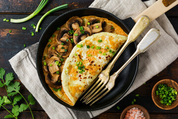 Fresh Scrambled Egg, omelette or frittata with mushrooms, onions and fresh herbs on cast iron skillet. Top view with copy space.