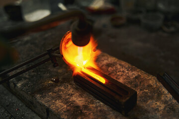 Goldsmith pouring melted metal into the mold