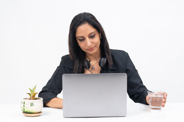 Portrait of professional Indian businesswoman working from her computer, Freelancer, work from home, Corporate lady reaching for glass of water.