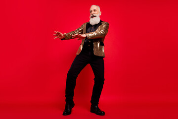 Full body photo of cheerful positive young man look empty space dance isolated on red color background