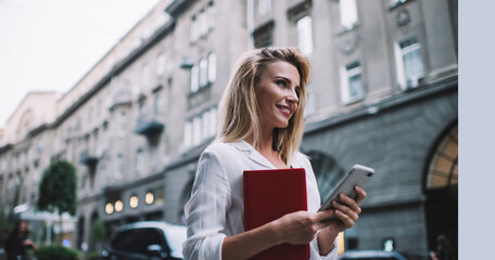 Fototapeta premium Positive woman using smartphone on street