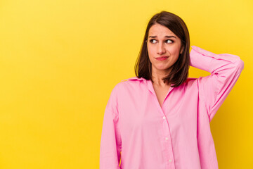 Young caucasian woman isolated on yellow background touching back of head, thinking and making a choice.