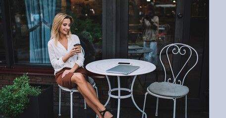 Charming lady with coffee to go in sidewalk cafe