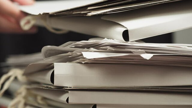 Stacking folders with documents in a stack with hands, counting files, searching for the right documents, a lot of paperwork and deadlines, office work concept.