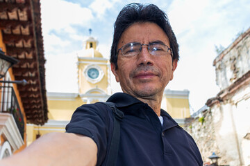 Hispanic man taking a selfie in front of arch of santa catalina at antigua guatemala
