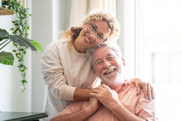 Smiling middle-aged woman hugging her senior father spending time together at home