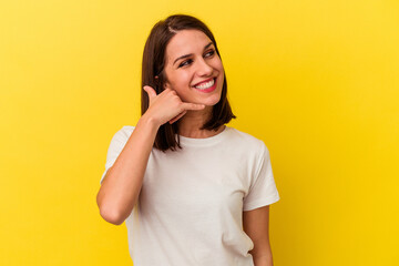 Naklejka premium Young caucasian woman isolated on yellow background showing a mobile phone call gesture with fingers.