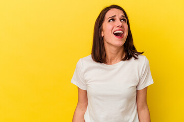 Young caucasian woman isolated on yellow background shouting very angry, rage concept, frustrated.