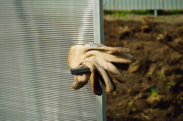 close-up of dirty work gloves hanging on the greenhouse door, signifying a break in work