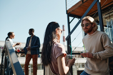 Waist up portrait of young people chatting on rooftop in urban setting