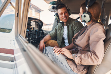 Joyful young man and woman sitting inside plane cockpit