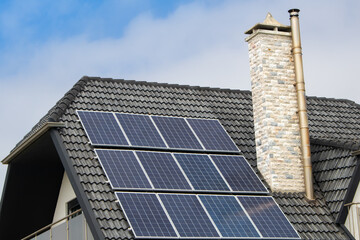 Detail of house roof with small solar panels or photo-voltaic modules