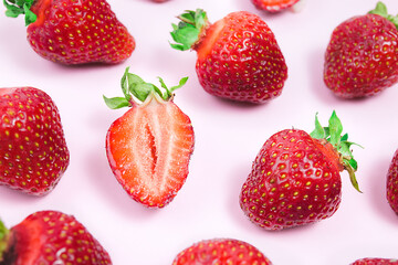 Strawberry creative pattern Sliced ripe red berry and whole strawberries with green leaves on pink background