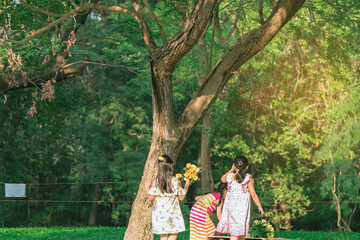Asian girls and friends playing together on lawn through green garden. Happiness girl friends having fun on field among trees and green grass. Happy friends spending time outside in green nature.