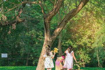 Fototapeta premium Asian girls and friends playing together on lawn through green garden. Happiness girl friends having fun on field among trees and green grass. Happy friends spending time outside in green nature.