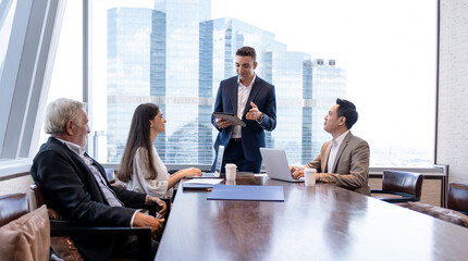 Businessman taking to business team in meeting room at office. Group of businesspeople talking,...