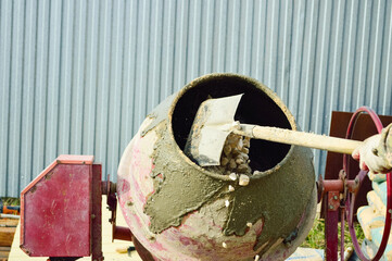 close-up - a worker throws rubble with a shovel into a concrete mixer to make mortar