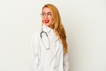 Caucasian doctor woman isolated on white background looks aside smiling, cheerful and pleasant.