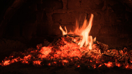 Logs of firewood burn out in the oven. Coals and flames in the fireplace.