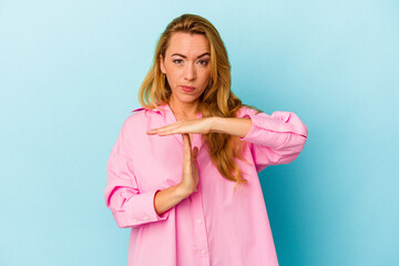 Caucasian woman isolated on blue background showing a timeout gesture.