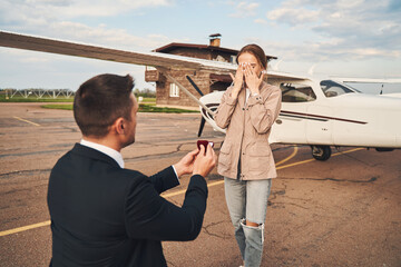 Loving man making proposal to his girlfriend at airdrome