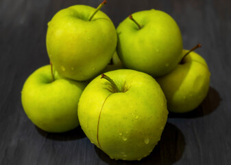 On a wooden background, a small number of green apples lies in close-up